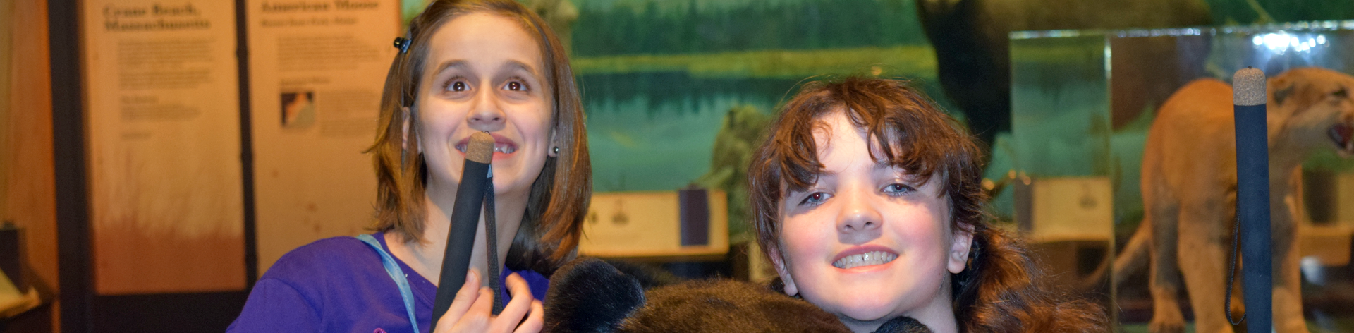 Two blind girls smile together at a museum.